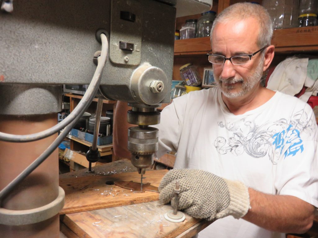 Tim drilling holes in metal pieces that Sherry will make into windchimes